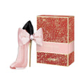 Pink high-heeled shoe with a bow next to a decorative perfume box on a white background
